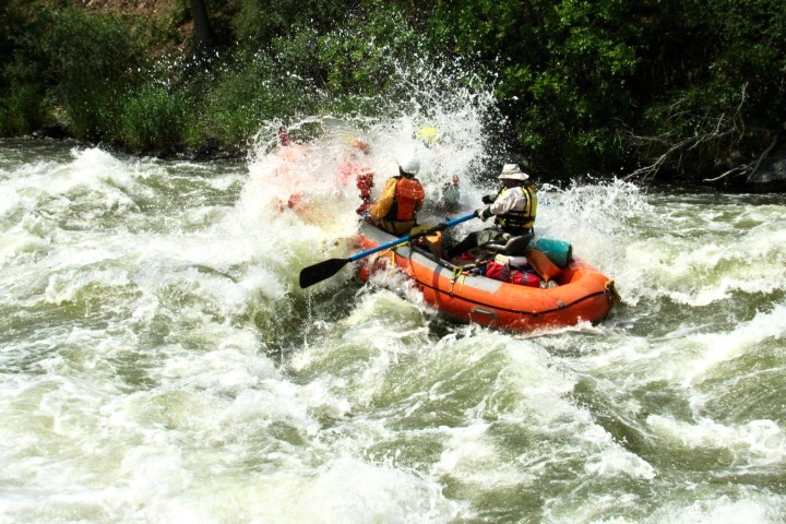 a man riding a wave on a raft in a body of water