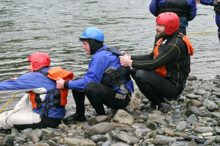 a group of people sitting on a rock next to a body of water