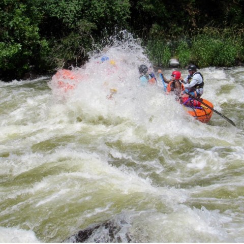 a man riding a wave on a raft in a body of water